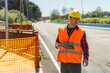 © Bohdan - Road construction worker using tablet near safety barrier on asphalt road