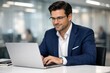 © VeerSaif - Professional businessman working on laptop, focused male executive in a modern office, corporate professional using technology for business tasks, confident manager at his desk