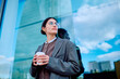 © we.bond.creations - Businesswoman standing outdoors holding a coffee cup, looking thoughtfully towards the urban landscape and reflecting on career goals