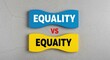 © Stocker Man - Equality vs Equaity conceptual text on blue and yellow blocks, social justice comparison on grey background, human rights and fairness concept