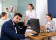 © JackF - Young woman stands at office desk and scolds group of upset man and women in office