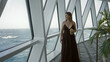 © Krakenimages.com - Young woman holding cocktail with cleavage visible at cruise ship deck rail, looking out to sea; relaxation.