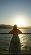© Krakenimages.com - Woman on cruise deck with bare back stretching by the rail at golden sunset over the sea; calm reflection.