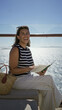 © Krakenimages.com - Woman reading a book on a cruise terrace building while holding the open book and smiling; vacation relaxation calm.