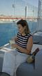 © Krakenimages.com - Woman sipping cocktail on cruise terrace, hand holding glass with pineapple garnish and sunglasses on head while seated on sofa; summer getaway relaxation.