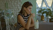 © Krakenimages.com - Woman stirs drink with straw at a table in a building by the water, sunglasses on head; contemplation moment.