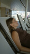 © Krakenimages.com - Woman reclining on a deck chair inside building atrium, leaning back with eyes closed and relaxed posture; relaxation.