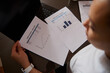 © Taras Grebinets - Businesswoman Reviewing Financial Charts and Invoices at Laptop Desk