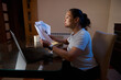 © Taras Grebinets - Woman Working From Home Reviewing Financial Documents At Laptop In Home Office