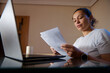 © Taras Grebinets - Woman Working From Home Reviewing Documents At Laptop In Home Office Workspace