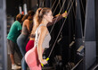 © JackF - Young woman pulling ropes down on ski ergometer, she increases endurance in crossfit training. Woman does exercises for a slim figure and muscle strengthening