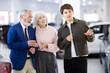 © JackF - Young car salesman presents car to mature man and woman at car dealership, discussing price and terms of sale