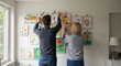 © lananh - Creative adults hang colorful kids artwork on a bright sunlit wall beautifully decorating their family home. AI Generated