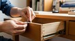 © MastiahVectra - Person assembling furniture drawer with hands on wooden desk indoors