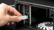 © Malik - A close up view of a hand inserting a silver USB flash drive into a computer tower port.