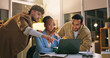 © peopleimages.com - Group, pointing and teamwork with laptop in business, working late or reporter with article deadline. Newsroom, online and people with smile for assignment, reading and creative with tech at night
