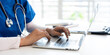 © Fahng - professional  doctor using laptop computer in hospital office watching medical webinar training, writing in healthcare report,