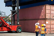 © NVB Stocker - Hispanic man harbor worker talking on the walkie-talkie radio and control loading containers at container warehouse. container yard port of import and export goods