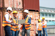 © NVB Stocker - Hispanic man harbor worker talking on the walkie-talkie radio and control loading containers at container warehouse. container yard port of import and export goods