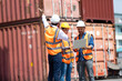 © NVB Stocker - Hispanic man harbor worker talking on the walkie-talkie radio and control loading containers at container warehouse. container yard port of import and export goods