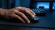 © faraz - A person's hand using a computer mouse on a desk in a dark room