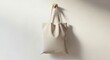 © mh - Minimalist beige tote bag hanging on a wall with shadow effect.