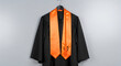 © Shopibizz - Black graduation gown with vibrant orange stole and tassel