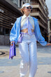 © Sunlight - Young woman confidently walking on urban street displaying trendy purple and blue fashion style
