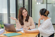 © Songsak C - Two Asian businesswomen collaborating and discussing financial project on laptop and documents in office.
