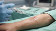 © MYKHAILO KUSHEI - Medical staff cleans a wound with sterile saline in a hospital setting during a procedure on a patient’s arm