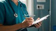 © Bayu Tri Nugroho - Healthcare professional in scrubs taking notes on a clipboard in a hospital setting for medical documentation and patient care