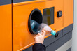 © Adam - Hand putting plastic PET bottle into a modern recycling vending machine, deposit return system and waste segregation, eco-friendly urban solutions, environmental protection and plastic recovery.