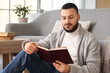 © Pixel-Shot - Handsome young man reading book on floor at home