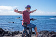 © luciano - Active senior man cycling along a scenic seaside coastline on a sunny day. Wearing a helmet, sunglasses, and casual sportswear, enjoying a healthy outdoor lifestyle and the freedom