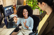 © Marko Geber - Smiling coworker greeting colleague at modern office desk