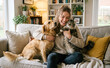 © svf74 - Young woman hugging her dog and cat on a cozy sofa at home. Happy pet owner, love for pets.