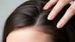 © Nur - Close-up of a person with smooth shiny brown hair and a hand gently touching the scalp showcasing healthy hair and scalp care routine for beauty and wellness enthusiasts
