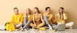 © Pixel-Shot - Group of students sitting on floor near pale yellow wall and drinking coffee