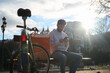 © Oscar - Courier taking a break on bench checking smartphone