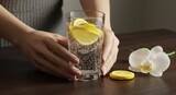 Woman holding refreshing drink with lemon slices near flower