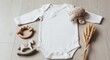 © udiana - Flat lay of a plain white baby bodysuit with cute accessories for newborn photos