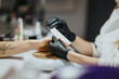 © qunica.com - A manicurist wearing black gloves files a client's fingernails during a manicure. The close-up shows hand care and nail shaping in a salon environment.