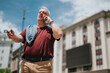 © qunica.com - Middle-aged man talks on a mobile phone while holding sunglasses and standing in an urban area. A casual business call captured on a sunny city street scene.