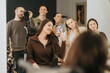 © qunica.com - A young woman takes a mirror selfie in a beauty center while friends and a photographer look on. She smiles in a salon chair as her friends pose behind her.