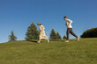 © Anna - Funny barefoot newlyweds joyfully run after each other on the green grass. A cheerful couple in love, a happy moment, the bride and groom