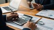 © graphic35 - Business people working with calculator and financial documents on wooden desk finance laptop