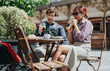© qunica.com - A man and a woman sit at a small outdoor cafe table drinking iced coffee and sharing pastries. They relax in business casual attire while chatting at a sunny urban sidewalk cafe.
