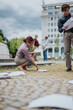 © qunica.com - A businesswoman and a colleague collect scattered documents outdoors near an office building. The coworkers bend to gather papers that have fallen across the pavement and grass.