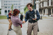 © qunica.com - Two business colleagues shake hands and smile while meeting outdoors in an urban plaza. A friendly professional greeting between coworkers in a city setting.