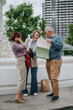 © qunica.com - Three business colleagues review documents and files while standing by a city fountain. A group of professionals discuss paperwork and plans in an urban outdoor setting.